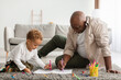 Leinwandbild Motiv African American Grandpa And Grandson Sketching Sitting On Floor Indoors