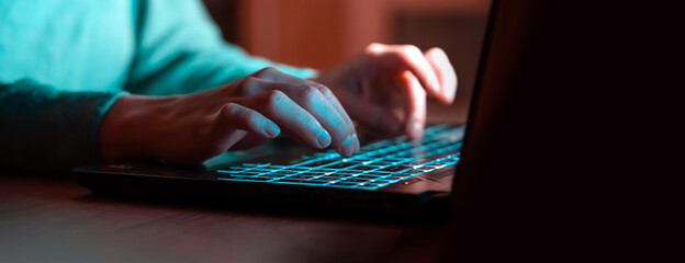 The girl works on the laptop at night, hands closeup.