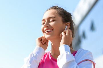 Wall Mural - Pretty young woman listening to music outdoors