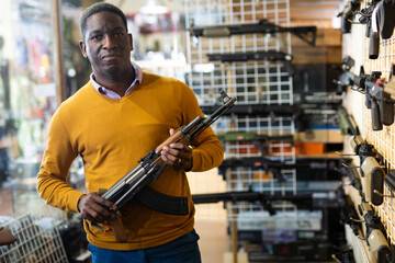 Wall Mural - African american guy in military equipment with weapon in army shop