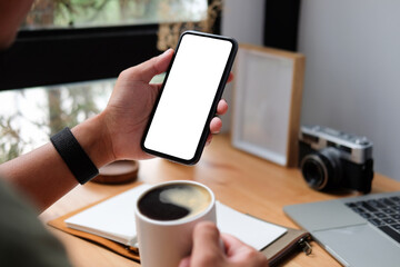 Wall Mural - young man sitting in home office and using smart phone.