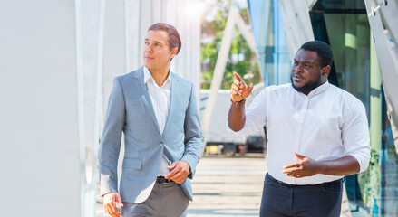 Wall Mural - Finance, business and cooperation concept. Two successful businessmen are talking on the street. Office workers are discussing business issues outdoor.