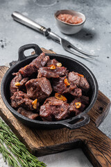 Grilled Sauteed Diced Beef in a skillet with garlic. Gray background. Top view