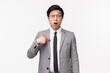 Waist-up portrait of surprised and confused asian businessman, office worker pointing at himself with disbelief and puzzled expression, being chosen or mentioned, standing white background