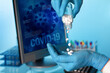 Researcher with oral pill bottle of pharmaceutical antiviral drugs against covid-19 coronavirus. Doctor hand holds antiviral pills and background screen with illustration coronavirus covid-19 data.