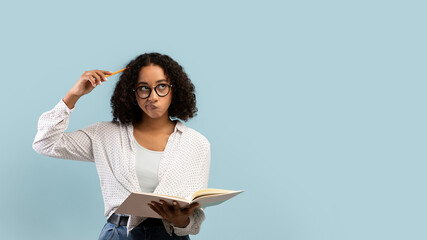 Thoughtful young black female student reading book, thinking over something on blue background, banner with copy space