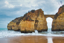 Ancient Stone Bridge Connecting The Mainland To A Small, Rocky Island, Lagos, Portugal, Algarve. Looks Like An Image From A Phantasy Movie.
