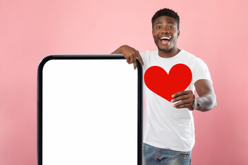 Black guy showing white empty smartphone screen holding paper heart