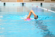 Swimmer trains in swimming pool using swimming equipment 