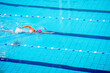 Swimmer swimming borstcrawl alone in an empty swimming pool while wearing a white swimming cap