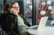 © LIGHTFIELD STUDIOS - Happy red haired freelancer talking on smartphone near laptop in hotel lobby