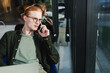 © LIGHTFIELD STUDIOS - Redhead man talking on smartphone near blurred laptop in hotel lobby