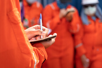 Wall Mural - A supervisor is taking note on paper during perform inspection audit and safety group meeting. People working in the industrial action scene photo. Close-up and selective focus at hand's part.