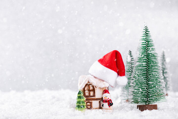 Wall Mural - Santa Claus Hat on Country house over silver background with New Year spruce trees on snow