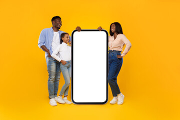 Black family showing white empty smartphone leaning on big screen