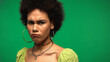 frustrated african american woman frowning and looking at camera isolated on green