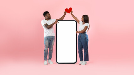 Wall Mural - Couple showing white empty smartphone screen holding paper heart