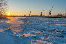 River Port. Railroad Bridge. Port Cranes. River Cargo Transportation. Winter. Frozen River. Sunrise