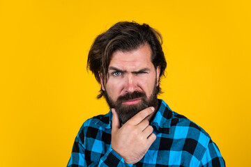 Wall Mural - posing for photo. mature guy with moustache on face. expressing human emotions. serious man in checkered shirt. emotional man on yellow background. brutal bearded hipster
