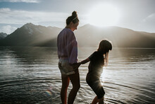 Sisters Standing On Edge Of A Lake On A Sunny Day