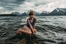 Young Girl Sitting On A Rock In A Mountain Lake