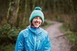 © Cavan Images - Portrait of laughing female trail runner in blue beanie and jacket