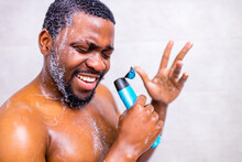 Attractive Young Cheerful Man Singing While Washing In The Shower, Holding Shampoo Bottle Like Microphone
