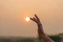 Silhouette Of A Young Girl Touching The Sun With Her Hand During Sunset