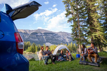 Friends Assembling Tent At Campsite Near Mountains
