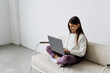 © F8  \ Suport Ukraine - Cute girl sitting on sofa with laptop at home