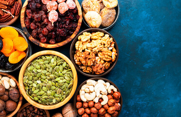 Wall Mural - Nuts and dried fruits in assortment. Dry apricots, figs, raisins, walnuts, almonds and other. Blue table background, top view, copy space