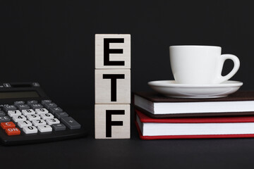 Wall Mural - wood blocks with coffee cup and calculator on black background with text ETF Exchance Traded Fund. acronym on wooden cubes Business concept