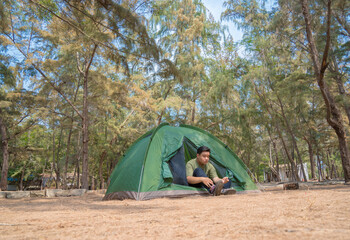 Focus asian young man puts a tent in the forest. Camp in the tent - tourist setting a tent on the camping. Travel, lifestyle concept.