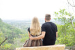 © Southport Images - Young couple sitting quietly together overlooking the forest from the mountain. Couple sitting on rock. Cloudy sky in the distance