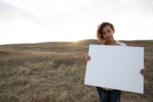Portrait Of Schoolgirl Holding Blank Signboard On Field
