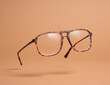 © Dima - Horn-rimmed glasses retro-style on pastel beige background. Levitation fashion accessory.