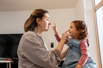 Sticker - family, hygge and people concept - happy mother and little daughter playing at home