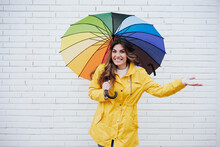 Happy Woman Standing With Multi Colored Umbrella In Front Of Wall