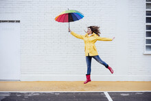 Happy Woman With Umbrella Jumping On Road