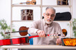 © Elnur - Old male repairman repairing musical instruments at workplace