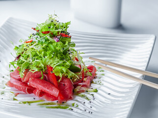 Sticker - Elegant salad with veal carpaccio in a white bowl with chopsticks.