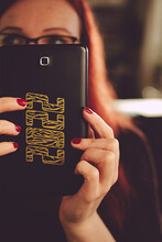 Luxury Golden 2022 Tiger Design Sticker On A Smartphone Hold By A Beautiful Red Haired Woman In Dark Red Dress. Red Painted Nails. Excessive Blur. Selective Focus. Portrait Orientation