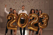 Leinwandbild Motiv Happy friends with golden 2023 balloons indoors. New Year celebration