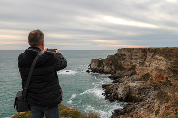 Wall Mural - A man make a photo of a beautiful coastline view from the top of a cliff.