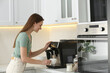 © New Africa - Young woman preparing fresh aromatic coffee with modern machine in kitchen