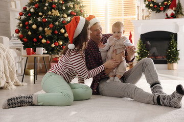 Poster - Happy family with cute baby on floor in room decorated for Christmas