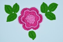 Crocheted Flower And Leaves On A White Paper Background

