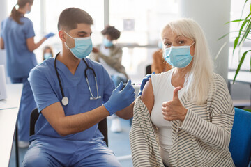 Wall Mural - Mature Woman Getting Vaccinated Against Covid-19, Showing Thumbs Up