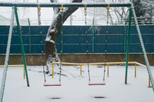 Snow Covered Swings In An Empty Playground