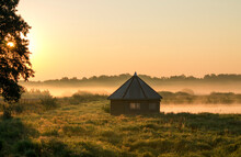 A View On Rural Bower In The Middle Of Wetlands During Foggy Morning Sunrise. Warm Colors.